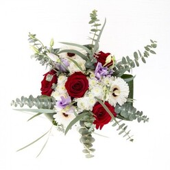To the eyes and senses, this carefully arranged bouquet reflects Ilford's vibrant character, blending tradition with contemporary flair. The red roses, with their intricate spirals and velvety depth, anchor the display, conjuring enduring affection and the deep roots found in local family traditions. Nestled among them are pristine white gerberas, each petal unfurling from a rich brown hub, exuding a freshness akin to spring mornings along Green Lane. Sprigs of lilac lisianthus, some gently unfurling and others standing in serene bud, thread between the bold blooms and offer a playful, modern touch-like the unexpected delights of Ilford's markets. A scattering of airy white filler flowers brings extra volume and softness, reminiscent of clouds drifting over the borough's lively parks. Eucalyptus leaves, their silvery-green hue shimmering in the sun, arch above and around, imbuing both visual interest and a subtle aromatic note. At the base, glossy green leaves wrap the stems with artistic intent, lending a tailored finish best appreciated by those familiar with Ilford's attention to detail. The clear glass vase completes the ensemble, exposing the verdant stems and pristine water within. This bouquet calms and uplifts, making it an ideal companion for new home celebrations, well-wishes to friends, or moments of quiet remembrance, all delivered with the thoughtful artistry found in Ilford's best local florist shops.