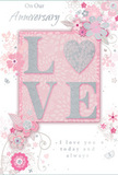 This anniversary card presents a gentle, romantic scene, blending pastel pinks and silvery greys into a design that feels as intimate and cherished as a quiet walk through Ilford's residential streets at twilight. At the centre of the card, the word "LOVE" is spelled out in soft, raised glitter, with each letter outlined delicately so that it glows against the blush pink background. The letter "O" is transformed into a shimmering silver heart, slightly textured, giving it the look of a polished charm nestled among petals. Around this focal point, delicate blossoms in blush, mauve, and soft white unfurl across the card like a painted garden. The blooms are rendered with an almost watercolour softness, their edges gently blurred and their centres detailed with fine lines that suggest the careful hand of an experienced florist designing a romantic arrangement for an Ilford anniversary delivery. Slender stems, loose swirls, and tiny leaves weave between the flowers, joined by subtle butterflies and floating petals that introduce a sense of light motion, as if a soft spring breeze were passing over an English garden. At the top and bottom, the phrases "On Our Anniversary" and "I love you today and always" are penned in elegant, understated script, balancing the artwork with heartfelt words. The overall impression is one of quiet celebration and deep affection, a keepsake that feels as tender and enduring as a favourite bouquet preserved in memory.